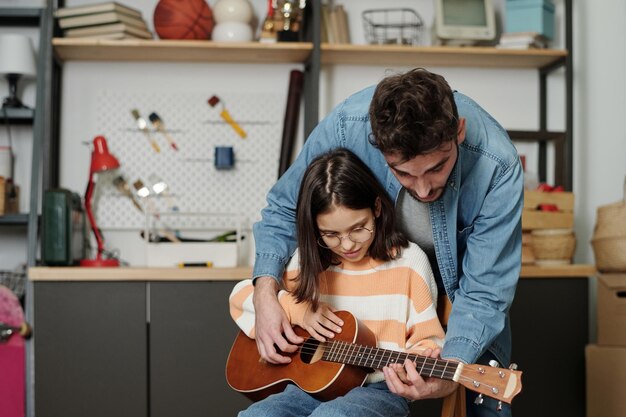 Hedendaagse jongeman die zijn schattige dochtertje leert gitaar spelen