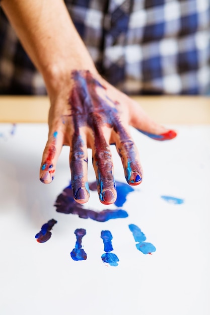 Hedendaagse kunsttrend Creatieve hobby en leuke vrije tijd Close-up van mannenhand vuil met verf die afdruk op wit papier achterlaat