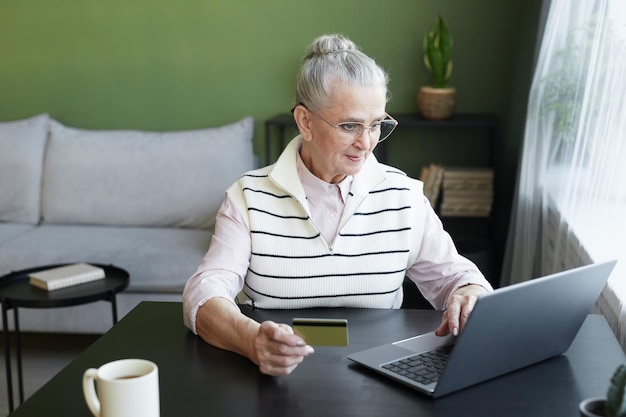 Hedendaagse senior vrouw in vrijetijdskleding kijken naar laptopscherm