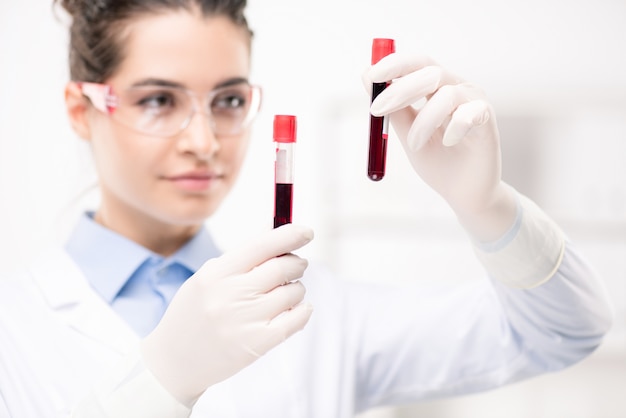 Foto hedendaagse vrouwelijke arts in handschoenen met monsters van nieuw vaccin ontwikkeld in medisch laboratorium