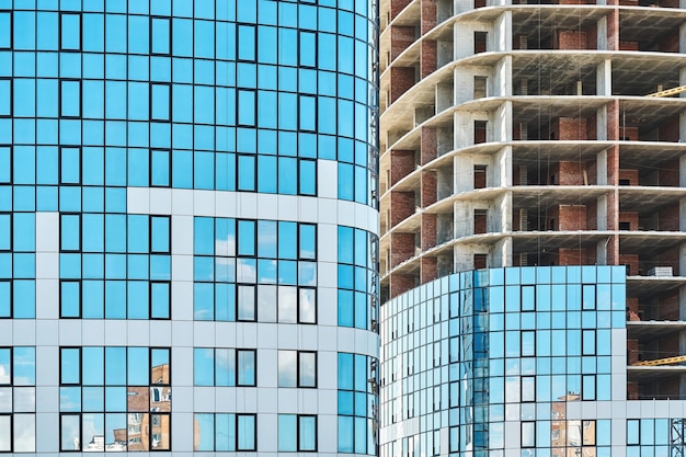 Hedendaagse wolkenkrabber gebouw met blauwe glazen gevel en hoogbouw karkas op de bouwplaats