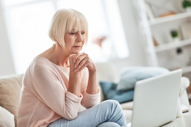 Heel contemplatie. Mooie senior vrouw die handen ineengeklemd houdt en aan iets denkt