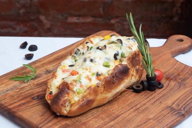 Heerlijk geladen brood gevuld met kaas, knoflook en groenten geserveerd op een houten plank