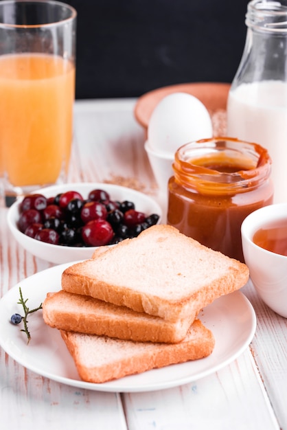 Heerlijk, gezond, stevig ontbijt op de witte tafel. eieren, havermout, melk, thee, bananentoost, huisgemaakte gezouten karamel, pannenkoeken met fruit, sinaasappelsap.