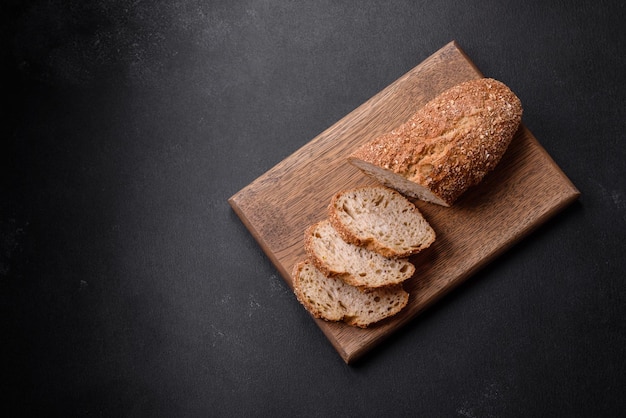 Heerlijk krokant brood met ontbijtgranen in plakjes gesneden op een houten snijplank op een donkere betonnen achtergrond