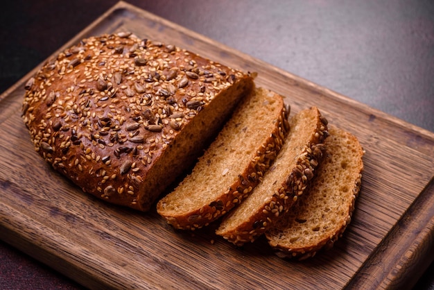 Heerlijk krokant brood met ontbijtgranen op een houten snijplank op een donkere betonnen achtergrond