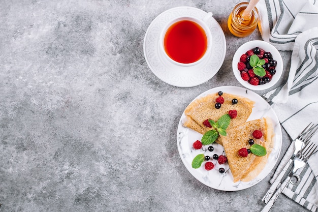 Heerlijk omfloerst ontbijt op grijze concrete lijstachtergrond. pannenkoeken met bessen