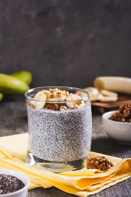 Heerlijk ontbijt chia zaden met bananen en walnoten in een glas op de tafel verticaal zicht