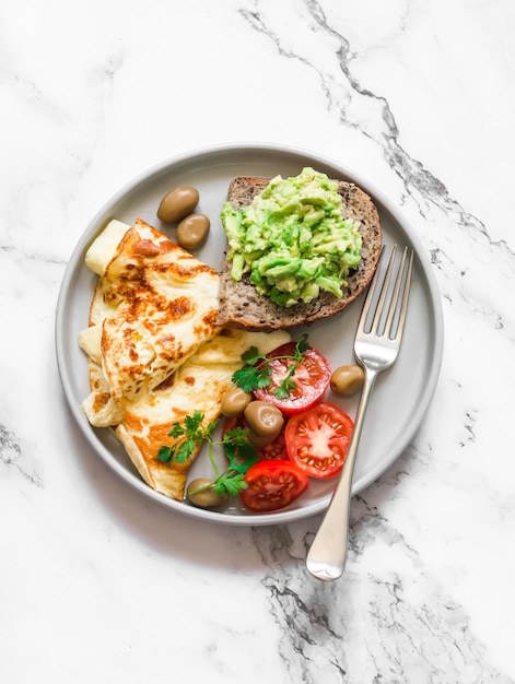 Heerlijk ontbijt omelet groenten avocado toast op een licht marmeren achtergrond bovenaanzicht