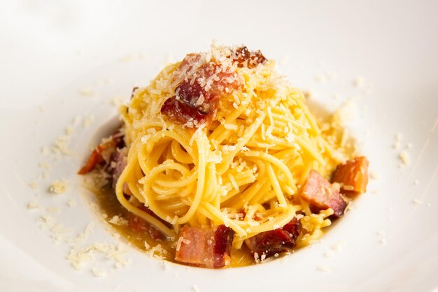 Heerlijk uitziende carbonara pasta met wat parmezaanse kaas en spek in een bord