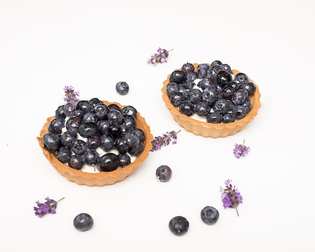 Heerlijk vers desserttaartje van zandkoekjes versierd met bosbessen tussen bessen en de lavendelbloemen. het concept van het bakken van bakkerij, zoet voedsel. geïsoleerde close-upfoto, exemplaarruimte.