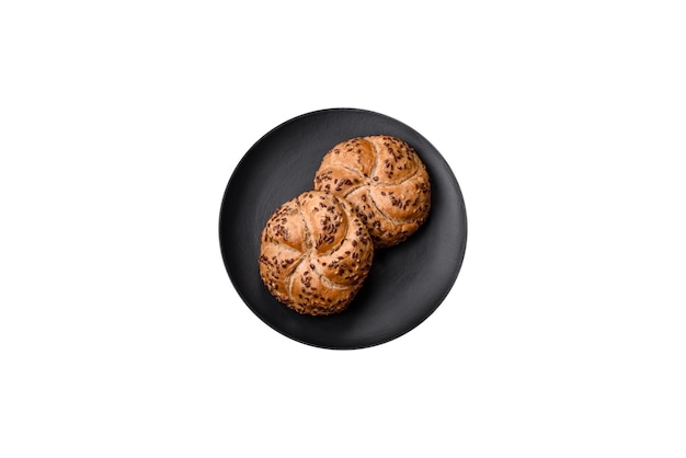 Heerlijk versgebakken knapperig broodje of kaiserbroodje met sesamzaadjes op donkere betonnen achtergrond