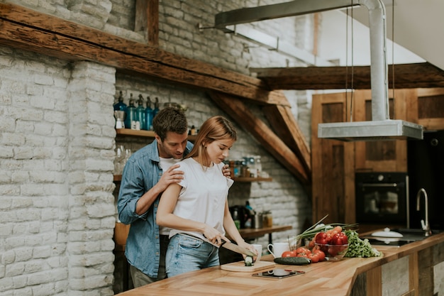 Heerlijk vrolijk paar samen kokend diner en het hebben van pret bij rustieke keuken