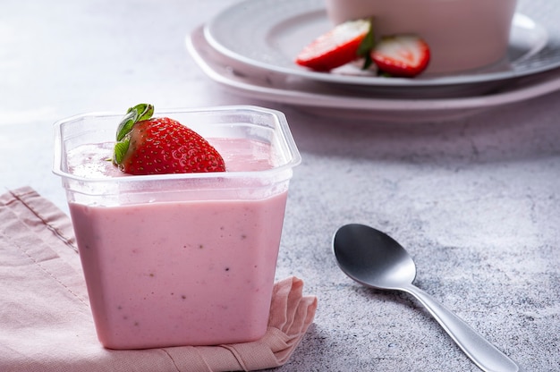 Heerlijke aardbeienmousse in een plastic beker voor levering met verse aardbeien. Ruimte kopiëren