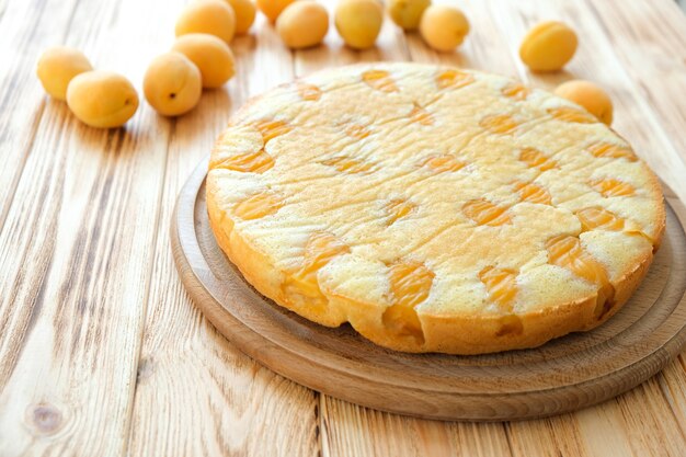 Heerlijke abrikozentaart op een houten bord met abrikozenvruchten op de achtergrond Eenvoudig recept voor zomercake