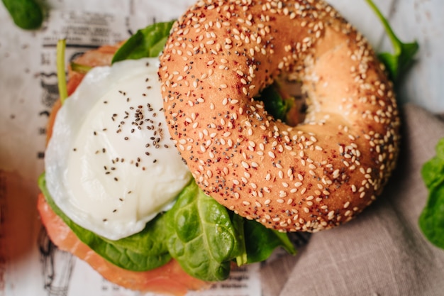 Heerlijke bagel met sesam- en chia-brood, van binnen bevat het zalm, gebakken ei en basilicum.