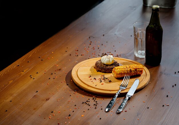 Heerlijke biefstuk hamburger met specerijen en kruiden op snijplank en leisteen tafel. Sappige gebakken vlees kotelet op houten snijplank