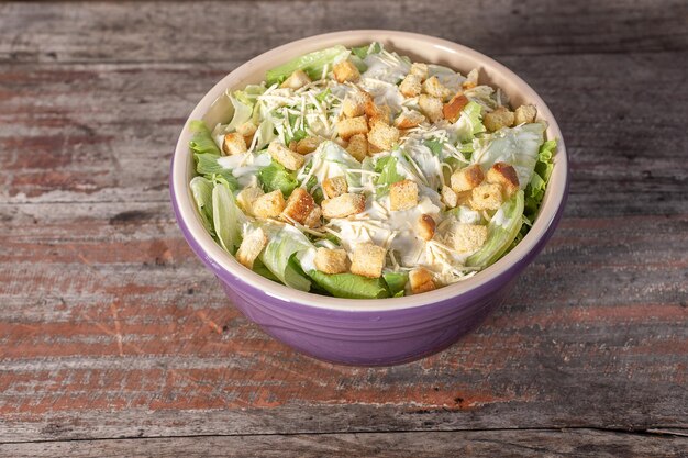 Foto heerlijke caesarsalade in kom op houten ondergrond