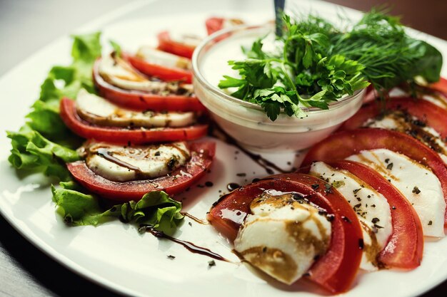 Foto heerlijke caprese salade met rijpe tomaten en mozzarella kaas met verse basilicum bladeren italiaans etenitaliaanse salade caprese salade plaat van gezonde klassieke caprese salade