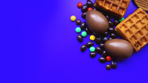 Heerlijke chocolade paaseieren, wafels, snoepjes op donkerblauwe achtergrond