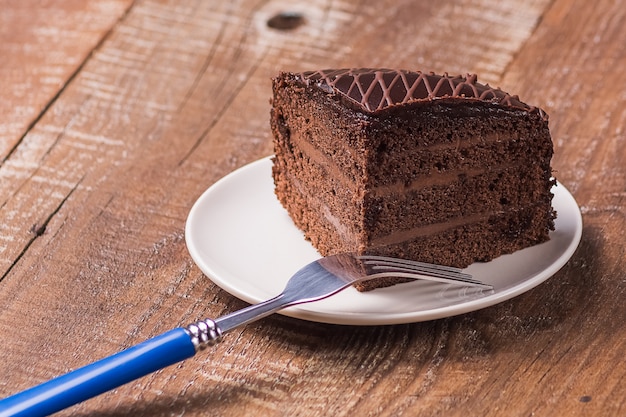 Heerlijke chocoladecake op een plaat op houten achtergrond.