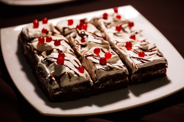 Foto heerlijke chocoladetaarten met botercrème, versierd met gelei van rode bessen op een witte plaat