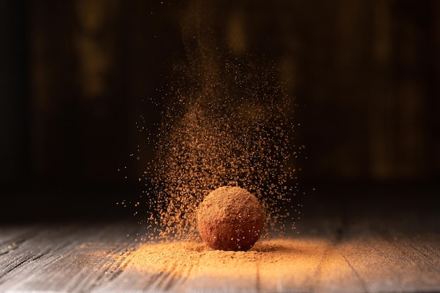 Heerlijke chocoladetruffels bestrooid met cacao op een zwarte reflecterende achtergrond