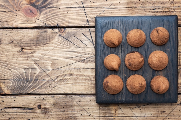 Heerlijke chocoladetruffels bestrooid met cacaopoeder op een houten standaard. Houten achtergrond. Kopieer ruimte.