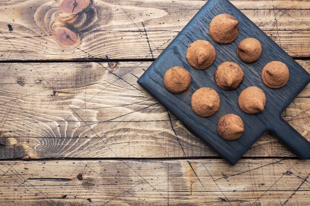 Heerlijke chocoladetruffels bestrooid met cacaopoeder op een houten standaard. Houten achtergrond. Kopieer ruimte.