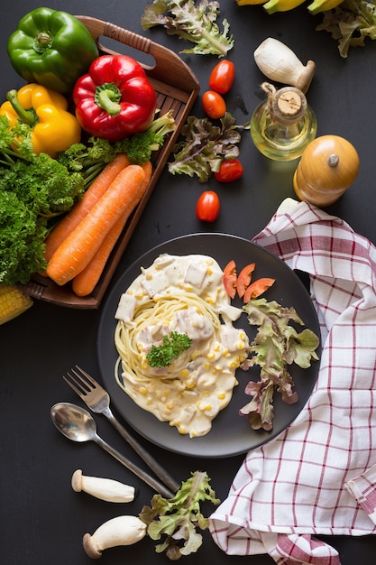 Heerlijke deegwarencarbonara met bacon en parmezaanse kaas in een zwarte kom op een zwarte achtergrond.