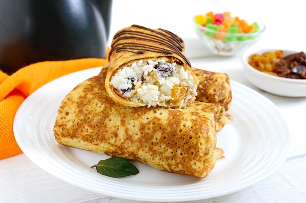Heerlijke delicate pannenkoeken met kwark en rozijnen op een witte houten achtergrond. Gezond ontbijt.