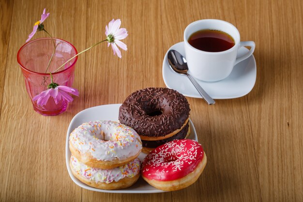 Heerlijke donuts op houten tafel met kopje thee