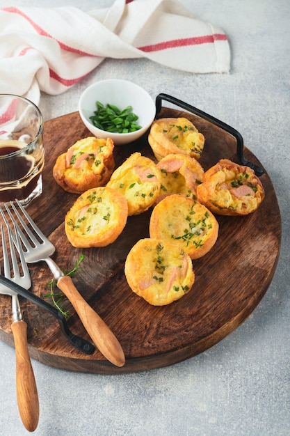 Heerlijke eiermuffins met groene uien, spek, kaas en tomaten op een houten bord op lichte achtergrond Gezond eiwitrijk en koolhydraatarm ontbijt Zelfgemaakt eten