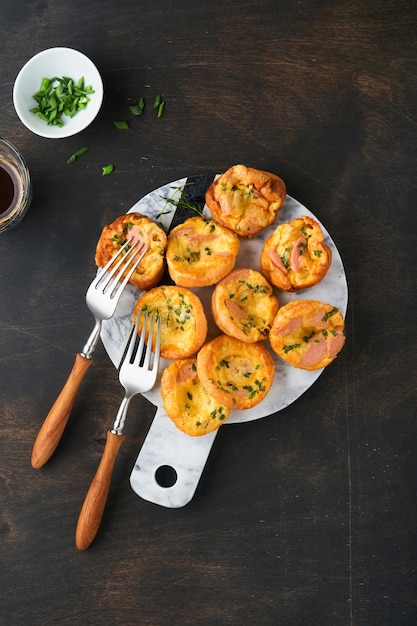 Heerlijke eiermuffins met groene uien, spek, kaas en tomaten op een houten bord op oude houten rustieke achtergrond Gezond eiwitrijk en koolhydraatarm ontbijt Zelfgemaakt eten