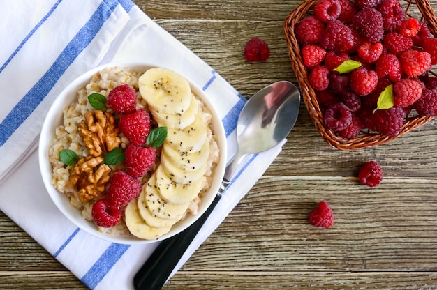 Heerlijke en gezonde havermout met banaan, frambozen, noten. Gezond ontbijt. Fitness eten. Goede voeding. Plat leggen. Bovenaanzicht.