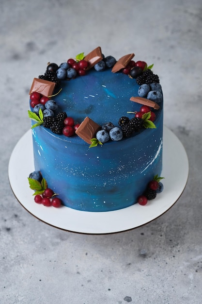 Heerlijke en mooie space style cake voor een jongen of een man. Suikerwerk voor de vakantie. Het dessert is versierd met verse bosbessen, bramen, rode aalbessen en chocolade.