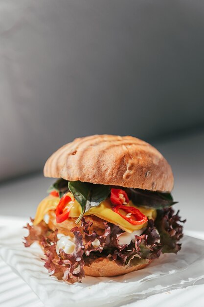 Heerlijke en smakelijke hamburger met kippenkotelet, basilicum en Spaanse peperpeper op een witte houten achtergrond