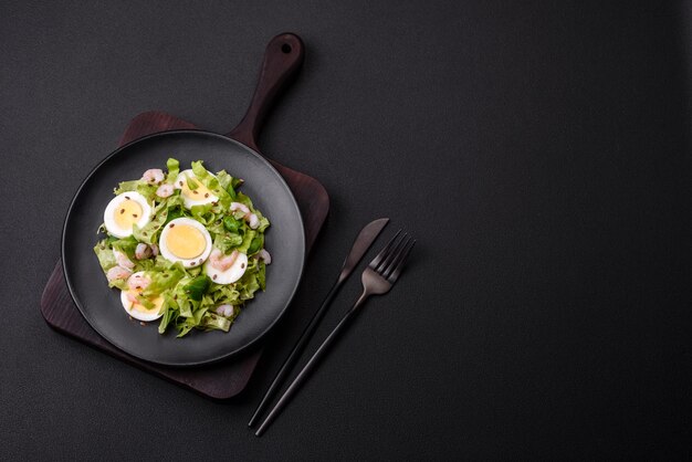 Heerlijke frisse gezonde salade met garnalen eiersla en lijnzaad op een zwarte keramische plaat op een betonnen achtergrond