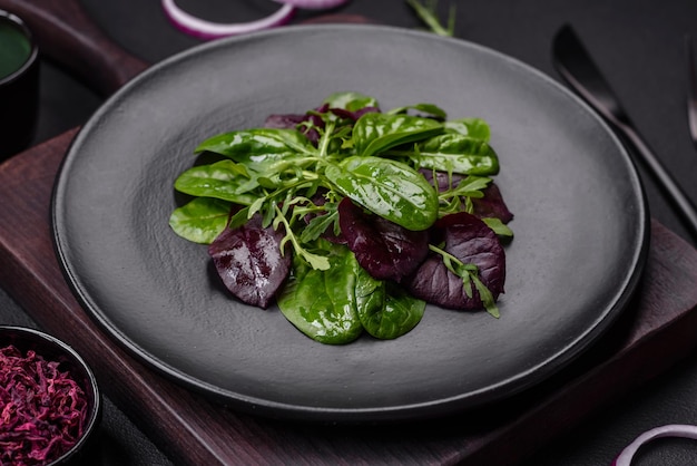 Heerlijke frisse salade bestaande uit spinazie, snijbiet, radicchio, rode grafiek, stierenbloed en rucola op een zwarte plaat op een donkere betonnen achtergrond