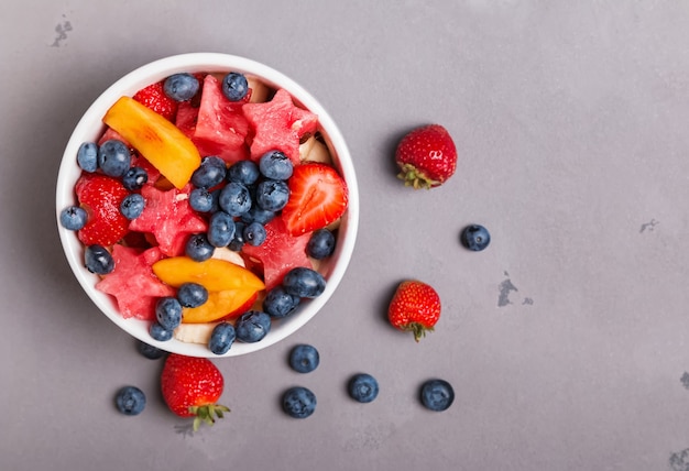 Heerlijke fruitsalade in een kom op de grijze achtergrond, bovenaanzicht