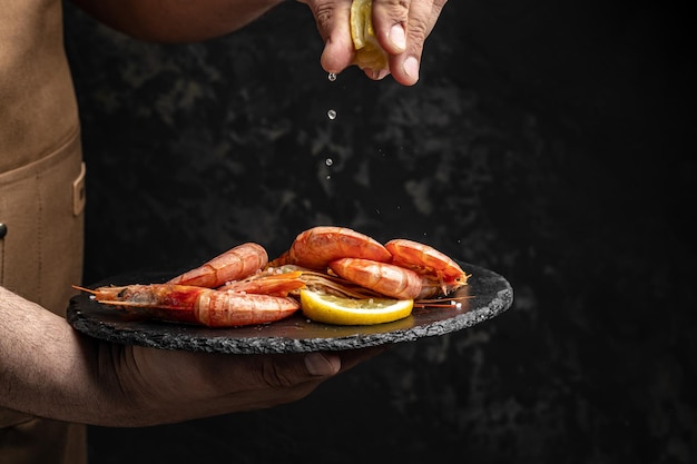 Heerlijke garnalen met kruiden Garnalen gebakken met spatten citroensap in een bevroren beweging op een donkere achtergrond Zeevruchtenvoorgerecht Culinair kookconcept