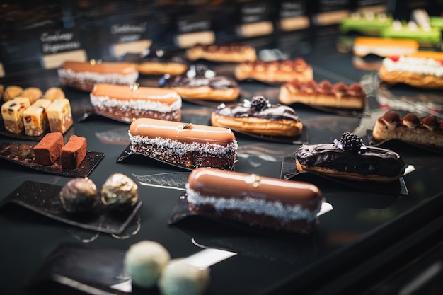 Foto heerlijke geassorteerde eclairs en zoetigheden op een zwarte tafel