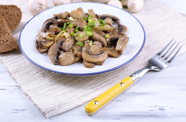 Heerlijke gebakken champignons op plaat op tafel close-up