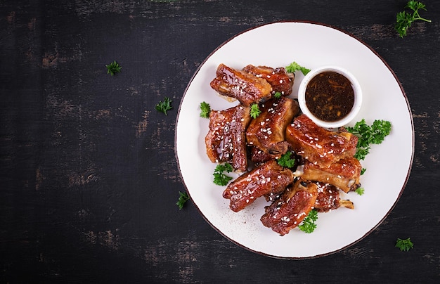 Heerlijke gebarbecued spareribs op plaat op donkere achtergrond Lekker bbq-vlees Bovenaanzicht plat lag