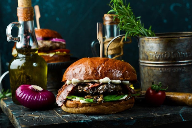 Heerlijke gegrilde hamburger met spek en groenten op een donkere achtergrond Fast food concept