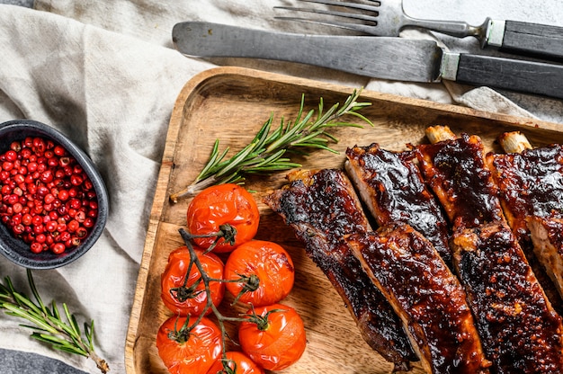 Heerlijke gegrilde ribben gekruid met een pittige braadsaus en geserveerd met gebakken tomaten. Grijze achtergrond. Bovenaanzicht