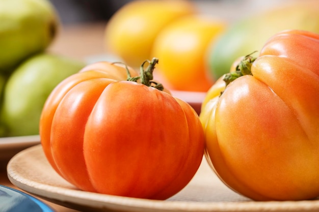 Heerlijke gerechten met superlekkere antieke roze tomaten op een houten getextureerde plaat omringd door ander fruit en groenten