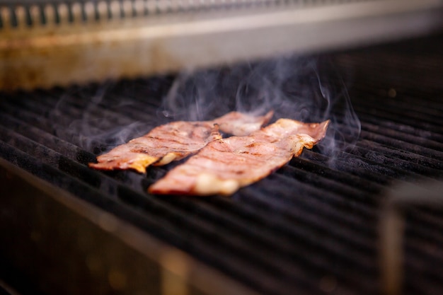 Heerlijke gerookte bacon op grill in keukenrestaurant. Voedsel voorbereiding