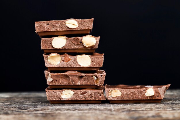 Foto heerlijke geroosterde amandelen en grote stukken chocolade op een houten tafel, close-up van natuurlijke cacaoproducten met toegevoegde suiker