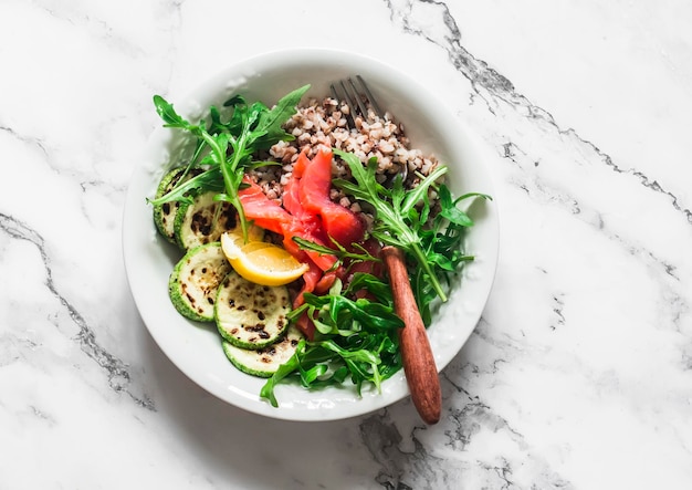 Heerlijke gezonde ontbijtlunch snack boekweit licht gezouten zalm squash rucola op een lichte achtergrond bovenaanzicht